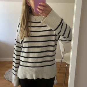 Vit och svart randig stickad tröja  - Säljer en vit stickad tröja med svarta horisontella ränder från 157. Tröjan har rund hals, långa ärmar och breda ribbade muddar vid ärmslut och nederkant. Materialet är en mjuk mix av viskos, polyester och nylon. Perfekt för dig som gillar chill och stilren look.