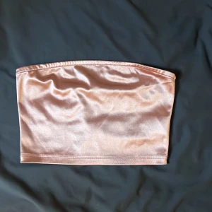 Rosa satin tubtopp  - Säljer en glansig champagnefärgad tubtopp från Divided. 