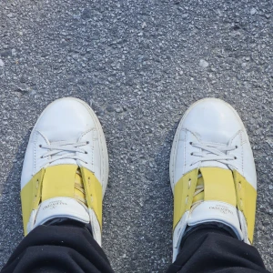 Valentino Open bytes - Snygga Valentino Open sneakers i vitt skinn med bred gul läderdetalj över snörningen. Klassisk rund tå, platt sula och diskret logga på plösen. Perfekt för dig som vill sticka ut med en färgklick i din outfit. 100 äkta! Bytes mot andra skor 