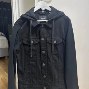 Svart jeansjacka med hoodie Jack & Jones - Svart jeansjacka från Jack & Jones i storlek L. Den är i storlek L men känns mer oxv passar mer dom som har S-M, knappts använd, stilren och riktigt snygg 