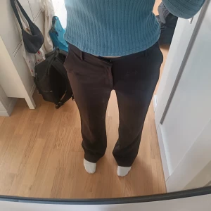 Svarta kostymbyxor med utsvängda ben - Snygga svarta kostymbyxor med utsvängda ben och klassisk passform. Modellen är Fiona från Lindex och har normal hög midja och normallånga ben. Mycket bra skick.