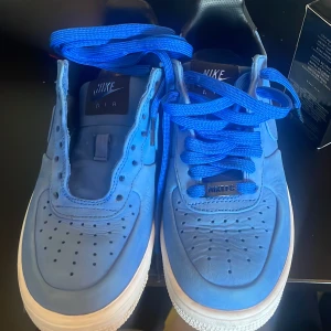 Nike Air Force 1 CR7 blå sneakers - Unika Nike Air Force 1 CR7 sneakers i blått med matchande blå skosnören och vit sula. Skorna har klassisk rund tå, perforerade detaljer och svart Nike Air-logga på hälen. Designade enligt Cristiano Ronaldos specifikationer. Perfekt för dig som vill sticka ut.