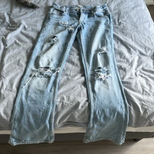 Ljusblå bootcut jeans Gina Tricot - Säljer ett par ljusblå bootcut jeans från Gina Tricot med slitna detaljer och hål på benen. Låg midja. Jeansen har klassisk femficksmodell och är tillverkade i jeansmaterial. Perfekta för en avslappnad och trendig look.