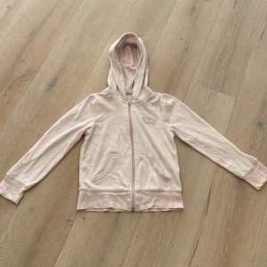 Ljusrosa hoodiejacka från H&M Young - Ljusrosa hoodiejacka från H&M Young med dragkedja framtill och två fickor. Jackan har en mjuk känsla, huva och diskret dekoration på bröstet. Perfekt för chill dagar eller när du vill ha en enkel och snygg look.
