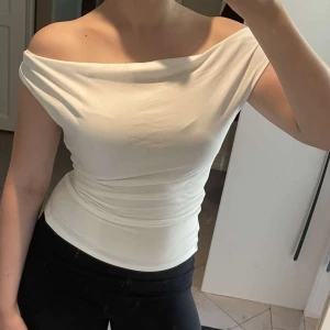 Vit topp - Vit off shoulder/ one shoulder topp i extremt mjukt material, passar perfekt till vita capri pants! Storlek S