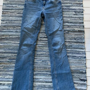 Blå bootcut jeans från Zara - Snygga blå jeans från Zara i klassisk bootcut-modell. Jeansen har normal passform och är tillverkade i mjukt denimtyg. Perfekta för dig som gillar en tidlös look med lite utsvängda ben. Färgtonen är mellanblå och materialet är bomullsjeans.
