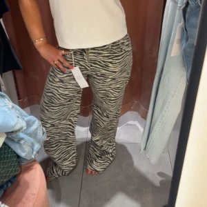 Zebramönstrade wide jeans - Säljer ett par riktigt coola jeans med zebramönster i svart och beige. Modellen är wide och har en avslappnad passform med låg midja. Perfekt för dig som vill sticka ut och addera lite edge till din outfit. Endast använda 2 gånger!! Nypris är 600!!