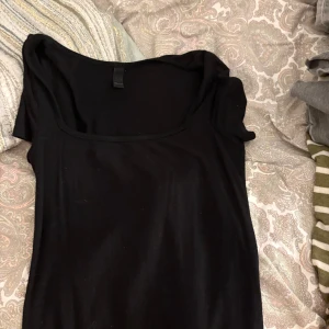 Svart kortärmad topp med fyrkantig ringning - En svart, stilren topp från Shein med korta ärmar och en snygg fyrkantig ringning. Perfekt att matcha med jeans eller kjol för en clean look. Mjuk och skön bomull som sitter bekvämt mot kroppen.