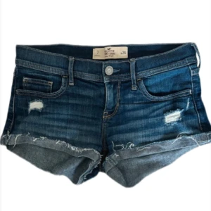 Hollister shorts - .PRIS GÅR ATT DISKUTERA VID SNABB AFFÄR‼️Säljer dessa suuupersnygga låg midjade Hollister shorts. De har uppvikta kanter &snygga  slitningar. Brodering bak. Köpa på vinted men storleken passade tyvärr inte mig. Storlek W26 (size 3)  midjemått: 38cm. 26=XS (34) 