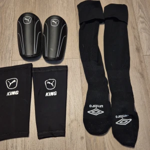 Fotbolls saker - Långa svarta fotbollsstrumpor från Umbro med grå förstärkning vid tå och häl. Strumporna är märkta med L och R för vänster och höger fot. Perfekta för match eller träning och designade för att sitta skönt i fotbollsskor.