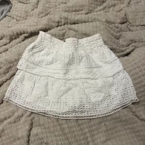 Vit broderad kortkjol  - Superfin vit kortkjol med broderade detaljer och spetskant. Kjolen har en bred midja och flera lager med volanger.  Jätte söt till sommaren och perfekt för den matchar till allt, den är både snygg och söt. Den är från Zaras barn edition men sitter som en xs