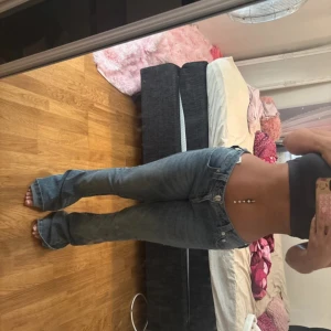 True Religion bootcut jeans låg midja - Säljer ett par klassiska blå jeans från True Religion med bootcut och låg midja. Jeansen har fem fickor, snygga sömmar och ikonisk patch bak. Perfekta för dig som gillar en avslappnad och trendig look. I nytt skick använder bara 4 ggr för att dom åkte ner på mig för va lite stora vid midjan 