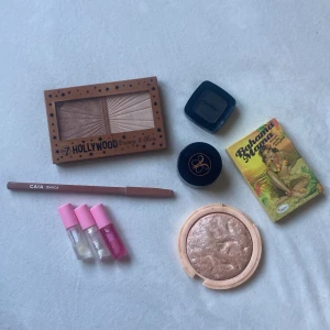 Stort sminkpaket med gloss & bronzer - Paket med tre små läppglans i rosa och glitter, CAIA läppenna i Bianca, W7 Hollywood bronzer/highlighter-duo, theBalm Bahama Mama bronzer, Anastasia ögonbrynsgel, en svart ögonskugga från kicks och en baked highlighter i champagne.