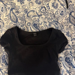 Svart kortärmad topp från H&M - En enkel svart topp från SHEIN med rund halsringning och korta ärmar. Perfekt basplagg att matcha med olika outfits. Mjuk och bekväm bomullskvalitet.
