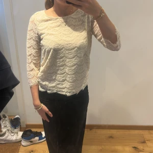 Vit spetsblus med trekvartsärm - Säljer en söt vit blus i spets med vackert mönster och trekvartsärmar. Blusen har rund halsringning och är lätt transparent med fina detaljer i spetsen. Perfekt att styla till både jeans och kjol.