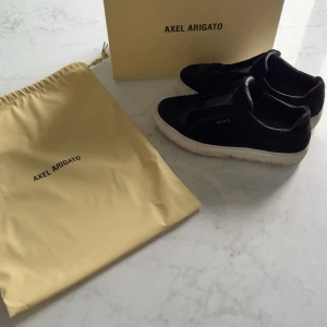 Svarta sneakers från Axel Arigato - Säljer ett par stilrena svarta sneakers från Axel Arigato med vit sula och diskret logga på sidan. Skorna har klassisk snörning och kommer med originalpåse och kartong. Perfekta för dig som gillar minimalistisk design. Storlek 39💕nypris 2950, mitt pris 1600
