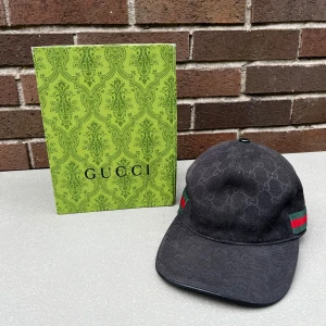 Svart keps från Gucci  - Säljer en svart keps från Gucci med diskret GG-monogram och klassiska gröna och röda ränder på sidan. Kepsen är i bra skick och har justerbar passform. Kommer med originalförpackning och dustbag.