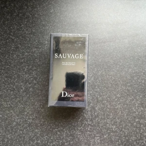 Sauvage Eau de Toilette 100 ml från Dior - Sauvage Eau de Toilette från Dior i 100 ml förpackning. Parfymen kommer i en elegant mörkblå kartong med silverdetaljer och tydlig Dior-logga. Doften är maskulin och fräsch, perfekt för dig som gillar exklusiva och moderna parfymer.