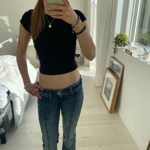 Svart croppad t-shirt från KappAhl - Svart croppad t-shirt från KappAhl, enkel och stilren design. Tillverkad i mjuk bomull med lite stretch för en bekväm passform. Perfekt till jeans eller kjol för en avslappnad look. Menad för barn men tycker den är väldigt snygg till större storlekar, som S. Väl använd men även bra omhändertagen.