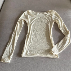 Ljusgul långärmad topp - Säljer en ljusgul långärmad topp i mjukt och tunt material. Modellen är tight och har rund halsringning. Perfekt att styla med jeans eller kjol för en enkel och fräsch look.