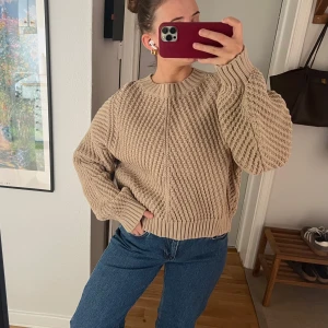 Beige stickad tröja från H&M - Säljer en beige stickad tröja från H&M med grov struktur och rund halsringning. Tröjan har lång ärm och en avslappnad passform, perfekt att styla med jeans eller kjol. Supermjuk och skön att bära!
