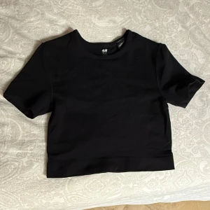H&M Move träningstopp - croppad t-shirt från H&M Move med rund halsringning och korta ärmar. I träningsmaterial tight passform