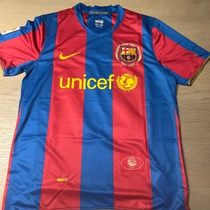 FC Barcelona Bojan 27 fotbollströja - Klassisk FC Barcelona fotbollströja med blå och röda vertikala ränder, gul Nike-logga och Unicef-tryck på framsidan. Nummer 27 och namnet Bojan på ryggen. Kortärmad modell i lätt och ventilerande material.