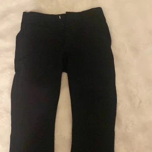 Svarta kostymbyxor från Lindex Kids - Säljer ett par svarta kostymbyxor från Lindex Kids i storlek 158. Byxorna har klassisk rak passform och är tillverkade i ett mjukt material som passar perfekt till en dressad look. Perfekta för dig som vill ha en stilren och enkel byxa. Det är dock et mönster kvar på insidan då jag sytt ipp det