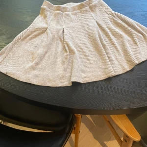 Beige ribbad kjol - Säljer en beige ribbad kjol med utsvängd passform. Kjolen är kort och har en mjuk, stretchig känsla som gör den bekväm att bära. Perfekt för dig som gillar en enkel men trendig stil.