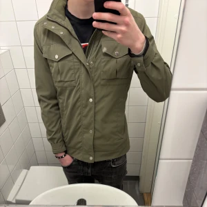 Olivgrön jacka från J.Lindeberg - Tja! Säljer en J.lindeberg jacka i den populära modellen bailey. Storlek M men kan passa en S om man har en hoodie under eller liknande. Perfekt nu till våren och lite varmare dagar då den är lite tunnare. Nypris ca 5500 kr.