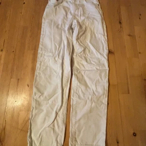 Vita straight jeansbyxor - Säljer ett par vita jeansbyxor med straight passform och normal midja. Byxorna har klassisk femficksdesign och stängs med dragkedja och knapp. Perfekta för en clean och stilren look.