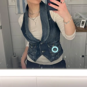 Mörkblå jeansväst med djup urringning - Snygg jeansväst köpt på sellpy. Aldrig använt då den är lite för stor för mig. Jag brukar ha s/m men skulle säga att den här är en M, dock lite större i brösten.