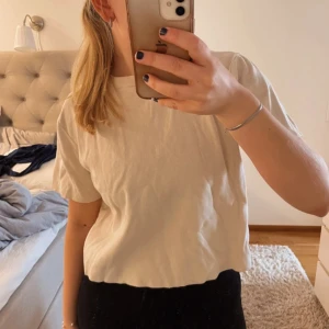 Beige t-shirt från H&M - En basic beige t-shirt från H&M i mjuk bomull. Modellen är croppad med korta ärmar och rund halsringning. Perfekt till jeans eller shorts för en enkel och clean look.
