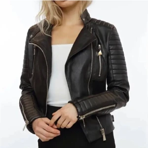 Svart skinnjacka med dragkedjor - Säljer en svart skinnjacka med coola detaljer som dragkedjor på ärmar och bröst, samt quiltade partier på axlar och armar. Jackan har en klassisk bikerstil och snedställd dragkedja framtill. Perfekt för en edgy look.