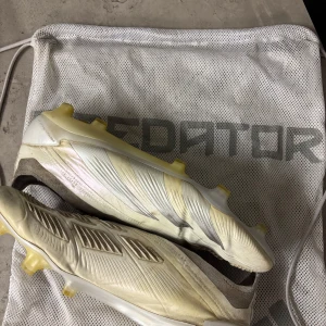Vita ADIDAS PREDATOR ELITE LACELESS FG - Säljer dessa för jag inte längre använder dem, bra skick men liten söm som spruckit på sista bilden, det är lätt fixat men inte gjort det, är öppen med prisförslag så bara att skriva!