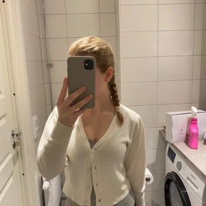 Beige kofta med knappar - Säljer en stilren beige kofta med knappar framtill. Perfekt för lager-på-lager och passar till många olika outfits. Koftan har långa ärmar och en klassisk design.