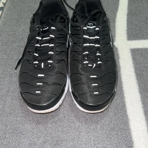 Svarta Nike sneakers - Snygga svarta Nike sneakers med vit sula och klassisk snörning. Skorna har en sportig design med diskreta vita detaljer och Nike-logga på sidan. Perfekta för en casual look.