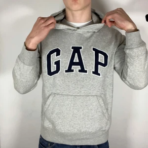 Grå hoodie från GAP - Säljer en klassisk grå hoodie från GAP med stor logga på bröstet. Tröjan har en bekväm passform och är tillverkad i en mjuk bomullsblandning. Perfekt för en avslappnad stil. 🩶 Liten på mig som är 180 74 kg. Kom med frågor, rekommenderar för folk som vanligtvis har S