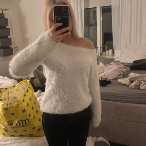 Vit fluffig offshoulder tröja - Säljer en supermjuk och fluffig vit tröja med offshoulder-design. Perfekt för att hålla sig varm och stilren under kyliga dagar. Tröjan har långa ärmar och en bekväm passform. Perfekt för mysiga hemmakvällar eller en avslappnad dag ute. ❤️❤️🥹