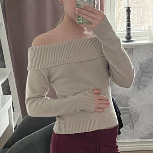 Beige offshoulder tröja - Säljer en stilren beige offshoulder tröja med långa ärmar. Tröjan har en bred ribbad kant vid axlarna och ribbade muddar vid ärmslut och nederkant. Den är finstickad. Perfekt för en trendig look! Använt typ 1 gånger. Kostade 300 kr när jag köpte den. Super skön och jätte söt 😍 