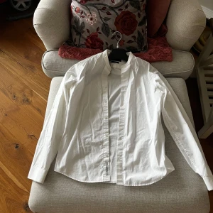 Vit skjorta med knappar - Klassisk vit skjorta med knappar framtill. Skjortan har långärmade ärmar och en stilren design som passar till många tillfällen. Perfekt för en elegant och tidlös look.