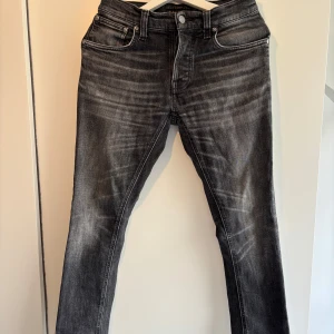  Nudie Jeans - Snygga svarta jeans från Nudie Jeans med en klassisk femficksdesign. De har en diskret tvättad look och är perfekta för en stilren vardagsoutfit. Storleken är 28W 32L