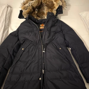 Svart dunjacka från Parajumpers - Säljer en svart dunjacka från Parajumpers med pälsfodrad huva och dragkedja. Jackan har flera praktiska fickor och en snygg patch på ärmen. Perfekt för kalla vinterdagar. Prislapp, extra knappar mm finns krav. Fler bilder kan skickas om önskas. Pris kan diskuteras 