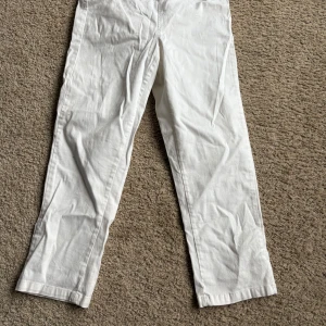 Vita ankelbyxor från Vero Moda - Snygga vita byxor från Vero Moda i en klassisk rak stil. Perfekta för en stilren look. Byxorna har en bekväm passform och är tillverkade i ett lätt material som passar bra för varmare väder.