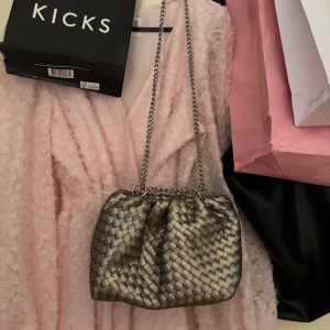 Silverfärgad handväska från Gina Tricot - As snygg silvrig handväska från Gina Tricot. Flätat mönster med kedja och ficka inuti. Passar perfekt till fest men även vardag. Använd få gånger, så som ny! Använd gärna KÖP NU💌💋