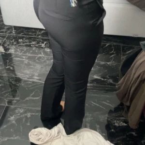 Svarta kostymbyxor - Snygga svarta kostymbyxor med en elegant och stilren design. Byxorna har en tight passform och är perfekta för en dressad look. De har en klassisk midja och stängs med dragkedja och knapp framtill. Säljer pga att det är försmå det är knappt använda och super bra skick 