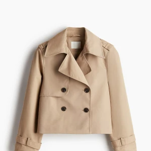 Beige trenchcoat - Snygg beige trenchcoat med dubbelknäppning och bälte i midjan. Jackan har långa ärmar och en klassisk krage. Använd 2 gånger och köpt på HM för 450kr, jag är en XS/S i vanliga fall men sitter bra som en L (kan skicka mer bilder om de behövs) och blir bara mer oversize😇❤️