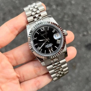 Seiko mod svart roman 40 mm - Nu är denna Seiko roman dial moden färdigbyggd och till salu. (Alltså en custom made). Klockan har Seikos automatiska NH35A driv-verk. Glaset är av safir vilket inte repas. Diametern är 40 mm. Klocklådan ingår. Övriga frågor? DM!