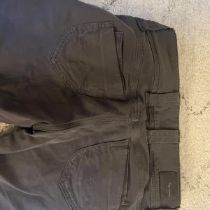 Low waist pepe jeans  - Säljer ett par mörkgrå byxor från Pepe jeans i modellen bootcut med låg midja. Byxorna har klassiska fickor både fram och bak samt stängs med två knappar och dragkedja. Perfekta för en clean och enkel stil. Står w10 men skulle säga xs/s. Mer tyg material än jeans material.