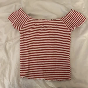 Röd- och vitrandig ribbad offshoulder topp - Säljer en söt offshoulder topp med röda och vita ränder. Toppen är ribbad och har korta ärmar. Storlek S